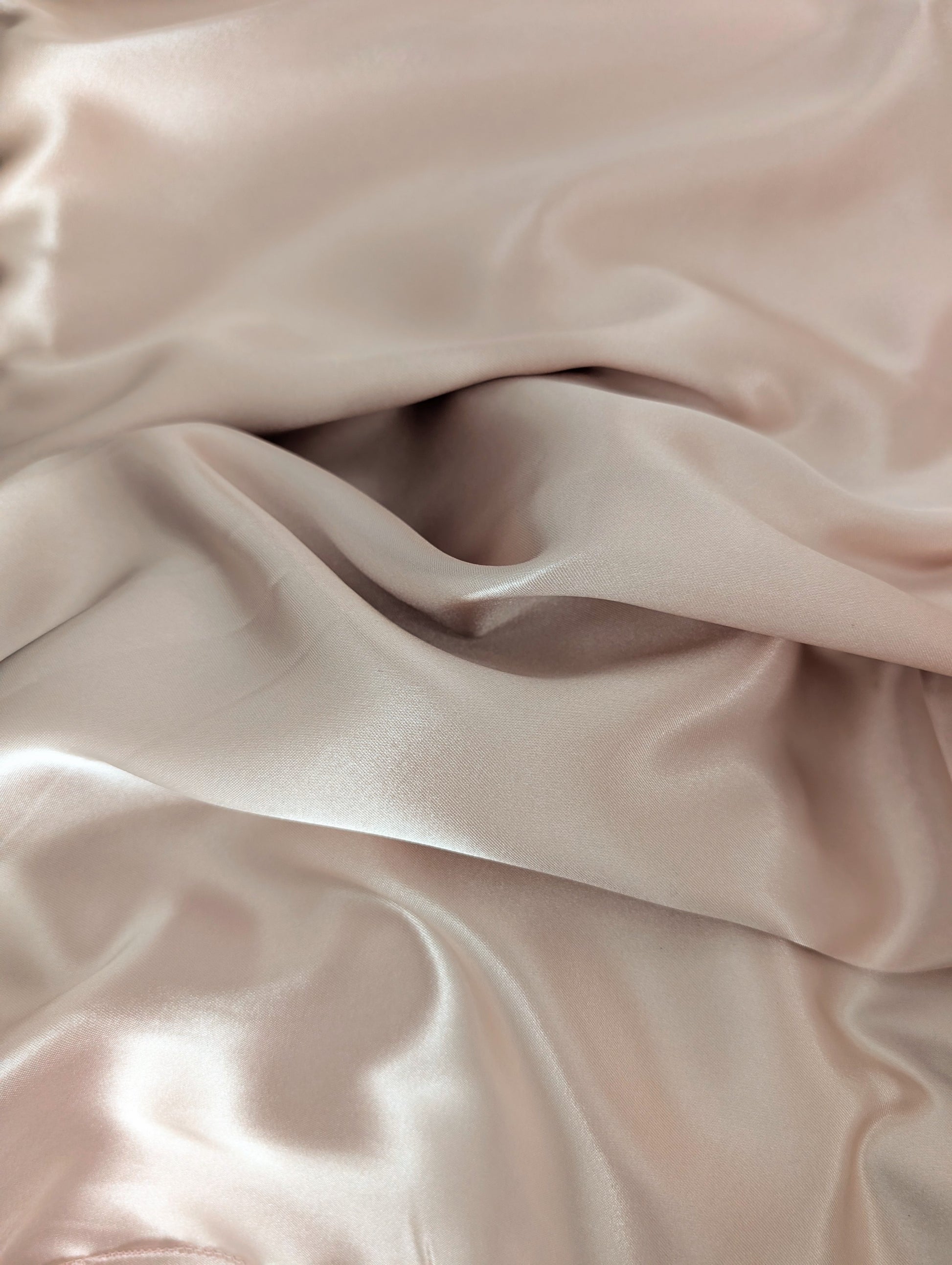 Close-up of smooth, light pink fabric with folds