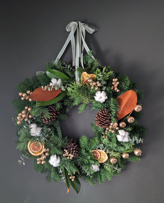 Decorative wreath with greenery, pinecones, and other elements on a dark background
